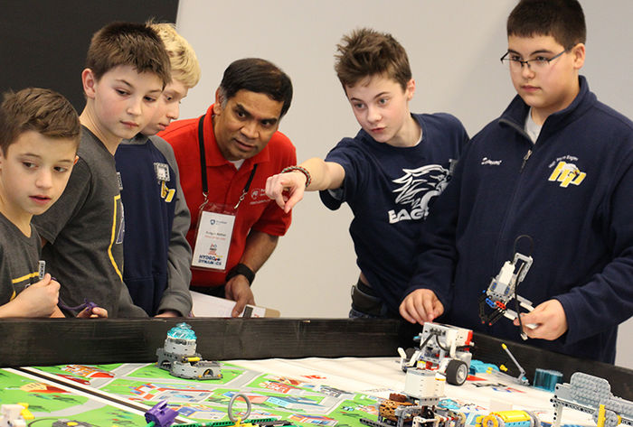 Dr. Rungun Nathan listens to a team's explanation of their robot's programming