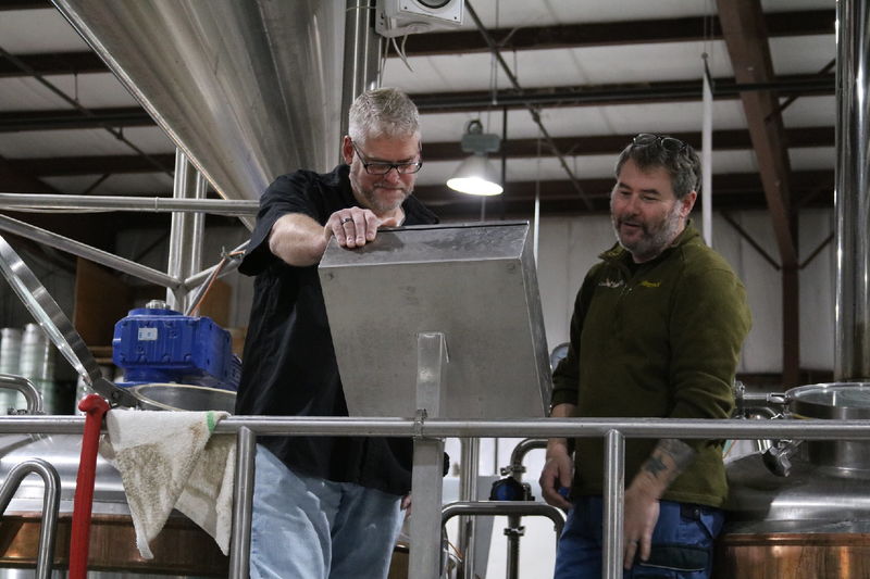 Two men looking thoughtfully at a screen in brewery