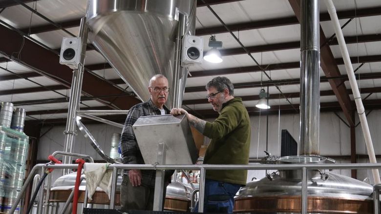 Two men in brewery looking thoughtful at screen
