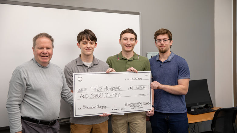 Male students pose for photo with $375 check