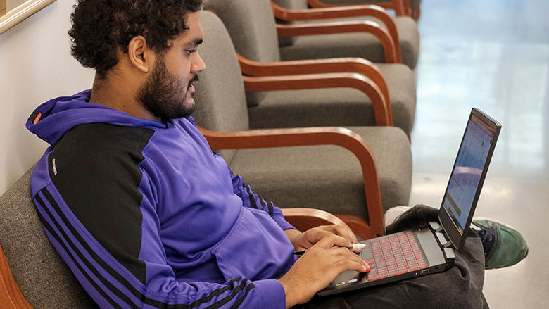 a student works on his laptop in a study space in Gaige