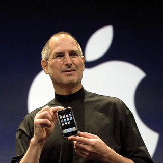 Photo of Steve Jobs holding iPhone in front of Apple logo