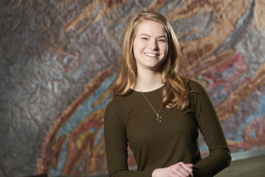 Sara Maholland standing in front of a topographical map of Pennsylvania