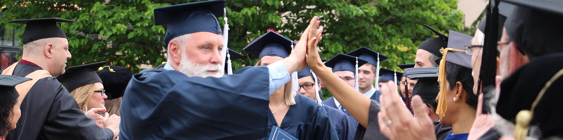 Adult Learner high fiving Faculty after Graduation