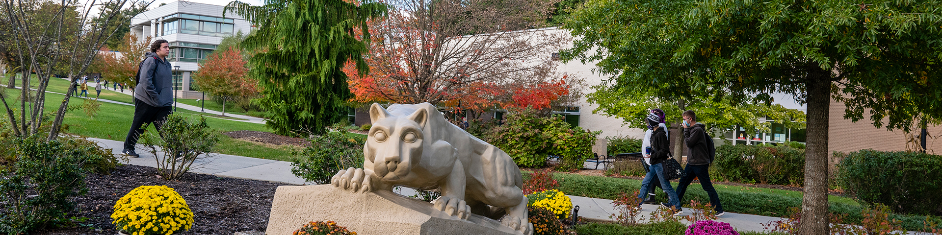 Students walking behind the Nittany Lion Shrine