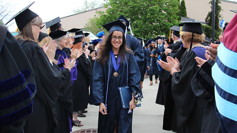 Denise Castro, student marshal for the afternoon ceremony, leads the graduates through the reception line of faculty, staff, administrators, and platform party members celebrating their achievement.