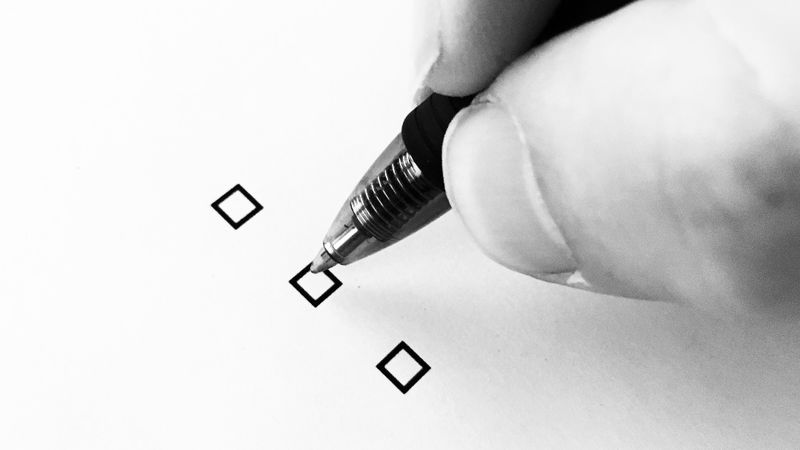 A person holding a pen, preparing to check a box on a piece of paper.