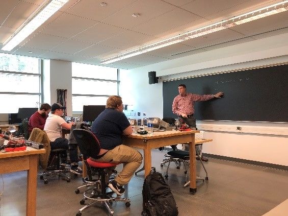 A professor teaching students in an engineering lab.