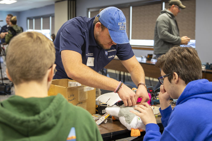 Penn State Berks student Nick Hall helps a high school solder the mechanics of a new button.