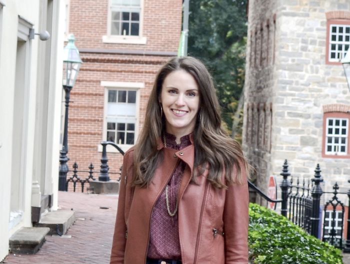 Jessica Schocker standing outside wearing a red jacket with stone and brick buildings in the background