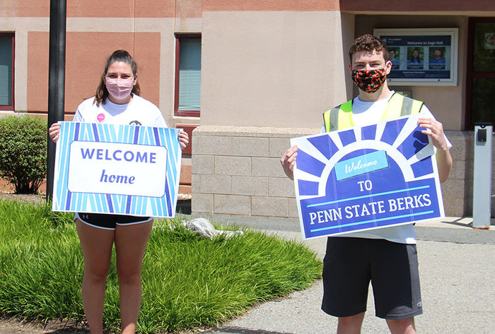 Orientation Leaders hold welcoming signs for incoming students.