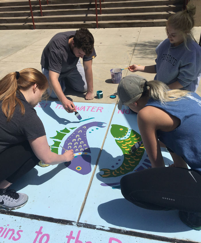 Students painting water safety murals on the sidewalk at elementary schools in Reading