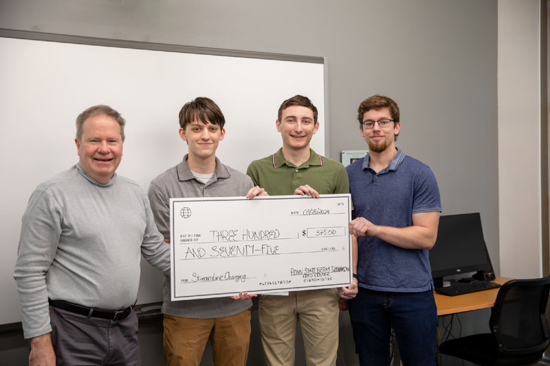 Male students pose for photo with $375 check