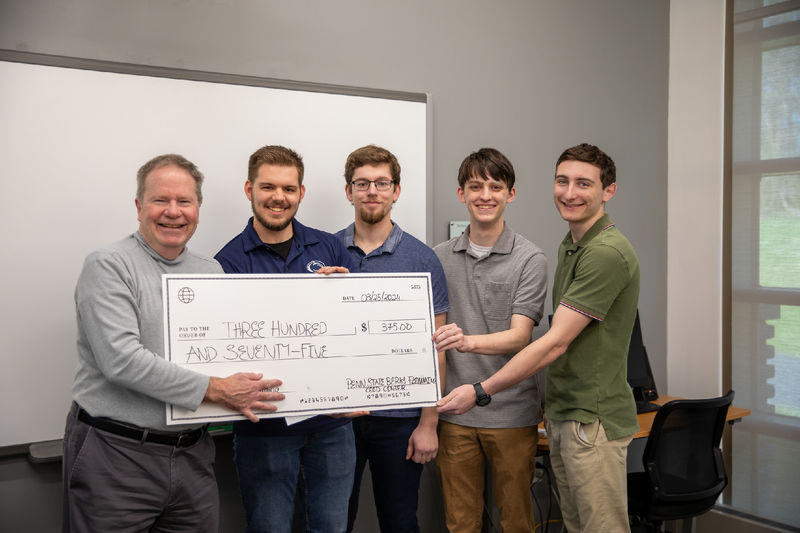 Group of male students pose for photo with $375 check