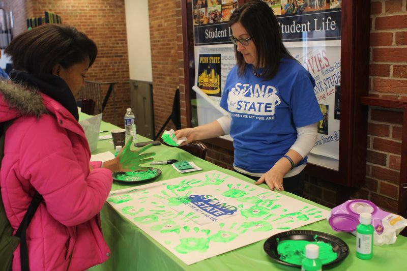 A student prepares to leave a green handprint on a poster