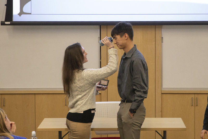 Female student presses makeup brush to male student's face