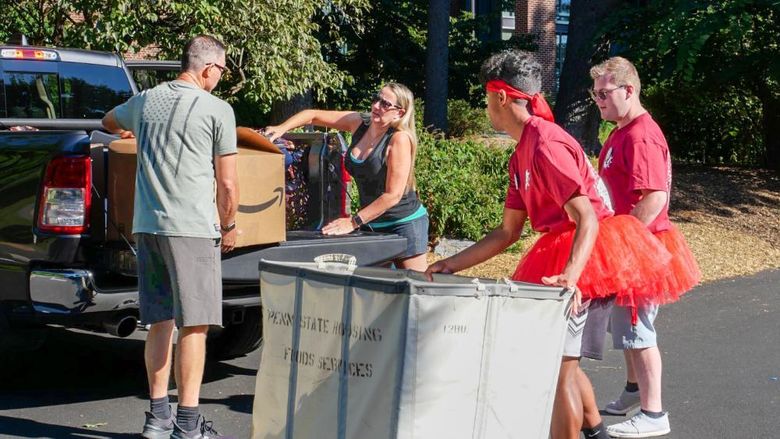 Two students help a family move boxes out of a truck.