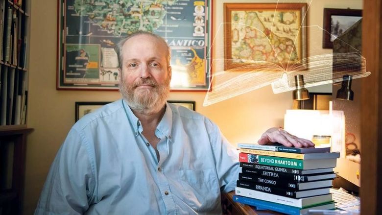 Randall Fegley sits at desk with books on top of it