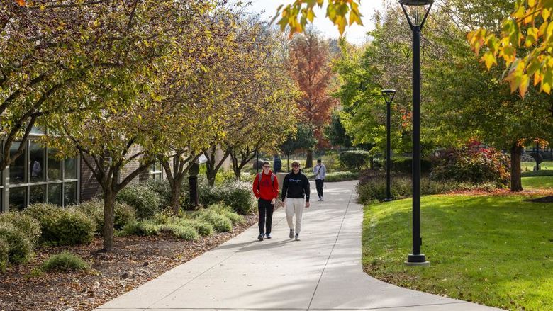 Two male students walk to class surrounded by fall foliage