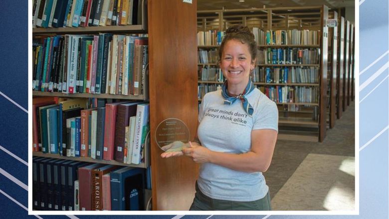 Person holding award in front of bookshelves