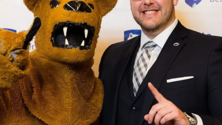 A person stands with the Nittany Lion, both hold up their index fingers