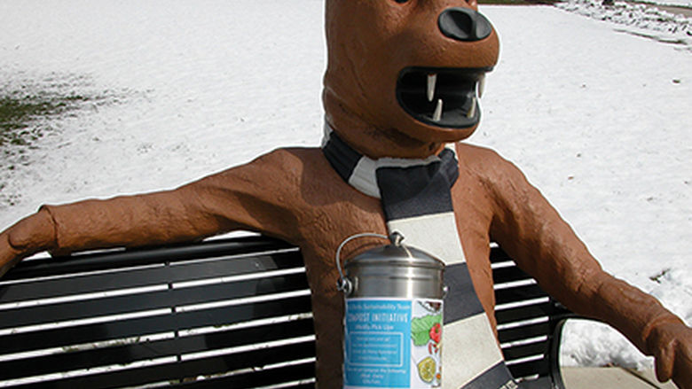 The Nittany Lion statue with a compost container. 