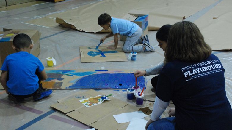 Children painting on cardboard