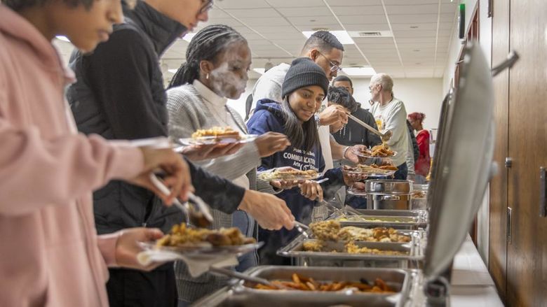 Students serve themselves food from chafing dishes.