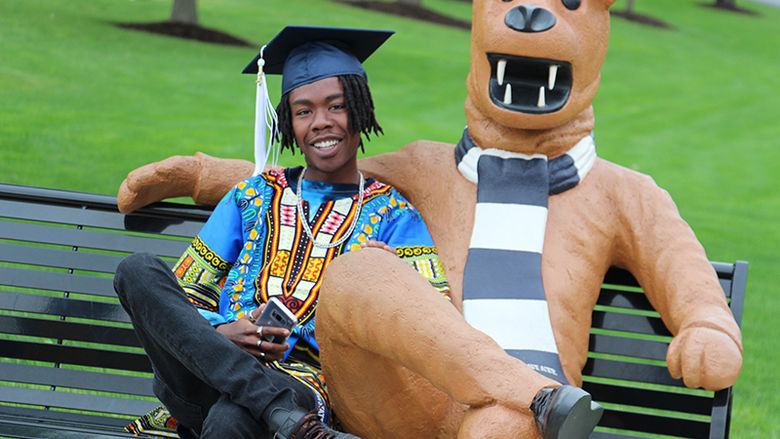 A student sits on the Berks Lion Bench after the graduation ceremony