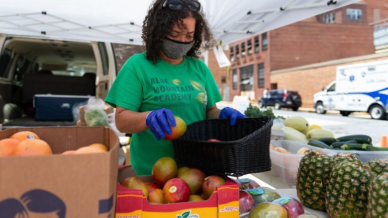 Christina Houston, a staff member of Blue Mountain Academy, arranges produce to be sold at the farm stand at Penn State Health St. Joseph Downtown Campus.