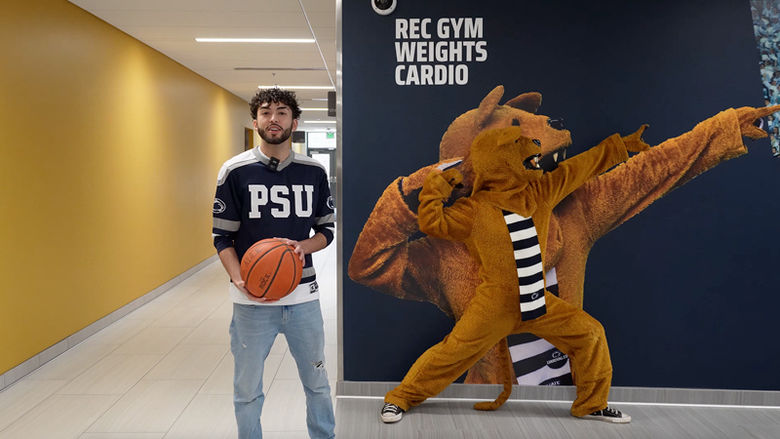 Edgar Marquez holds a basketball in the Beaver Center hallway with Nittany Lion