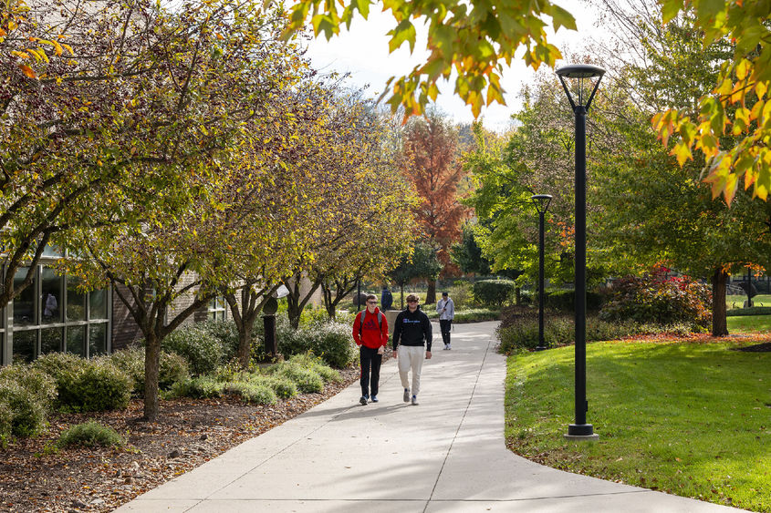 Two male students walk to class surrounded by fall foliage