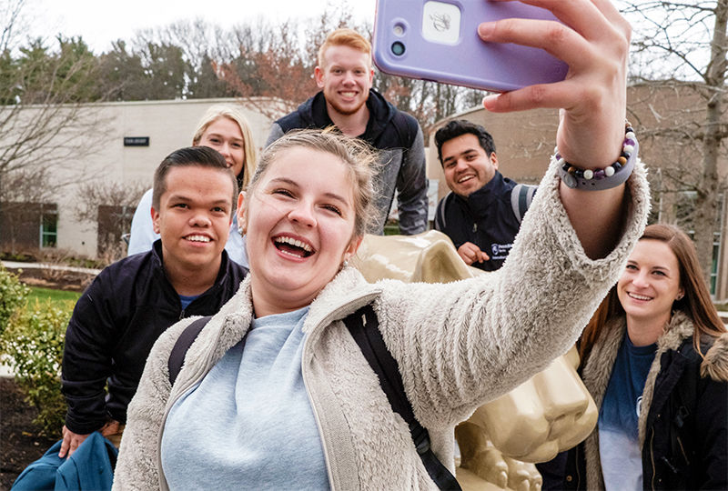 Students take a selfie around the lion shrine at Penn State Berks.