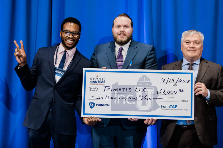 Penn State President Eric Barron, right, awards $2,000 at the 2018 Invent Penn State Venture & IP Conference to Trimatis' Tito Orjih, left, and Jason Lehrer.