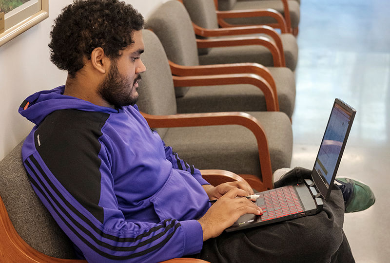 a student works on his laptop in a study space in Gaige