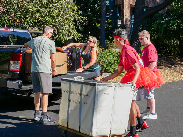Two students help a family move boxes out of a truck.