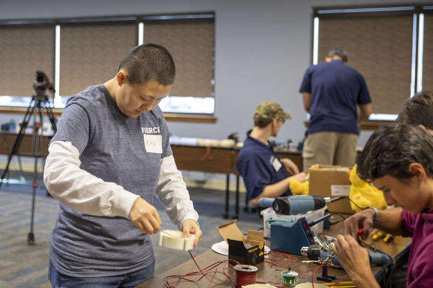 Berks student helps high school student with soldering toys.