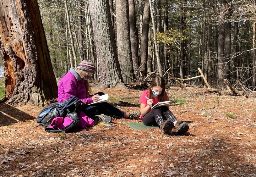 Adult and child work on nature journals outdoors