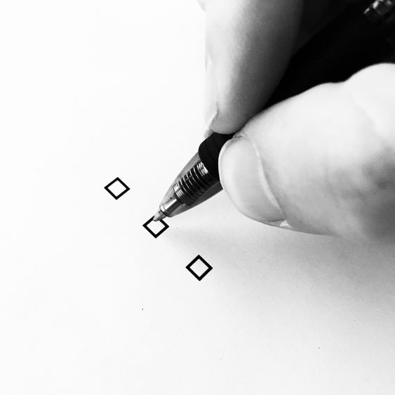 A person holding a pen, preparing to check a box on a piece of paper.