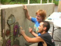 Bev Leviner works with volunteer on mural